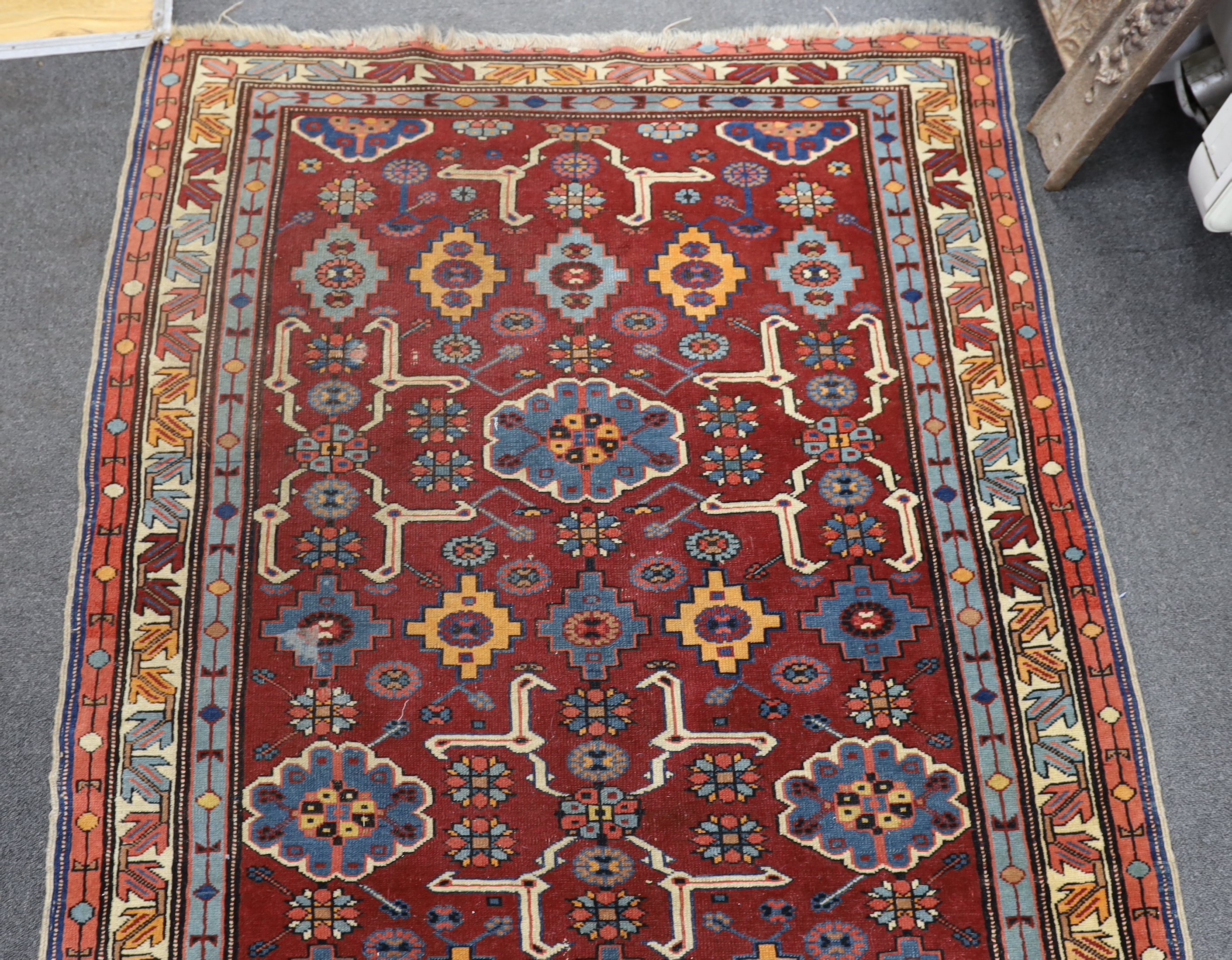 A Caucasian burgundy ground rug, 220 x 128cm